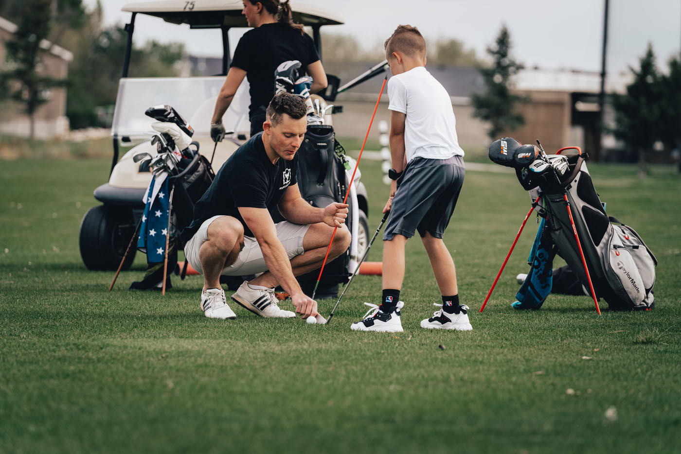 A Tee Box employee working with a group of kids on a golf course in Granger, IN.